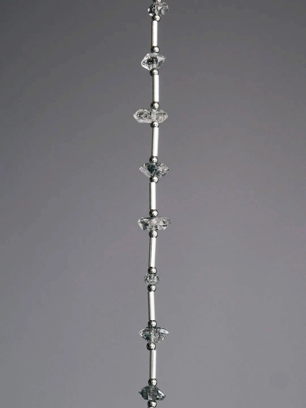 Close-up of raw Herkimer-style flash quartz, sterling silver tubes, and skin-friendly titanium steel spacer beads