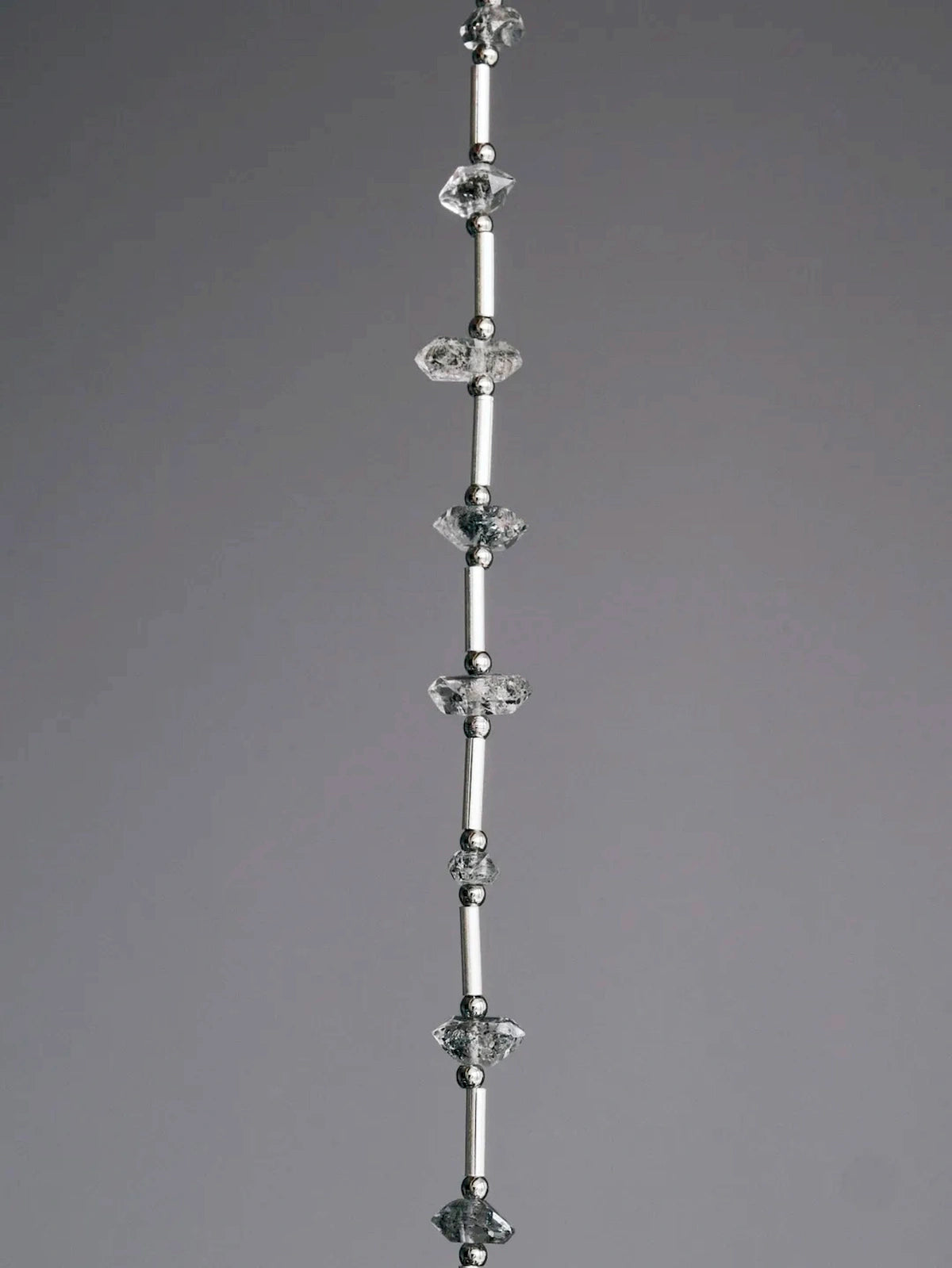 Close-up of raw Herkimer-style flash quartz, sterling silver tubes, and skin-friendly titanium steel spacer beads