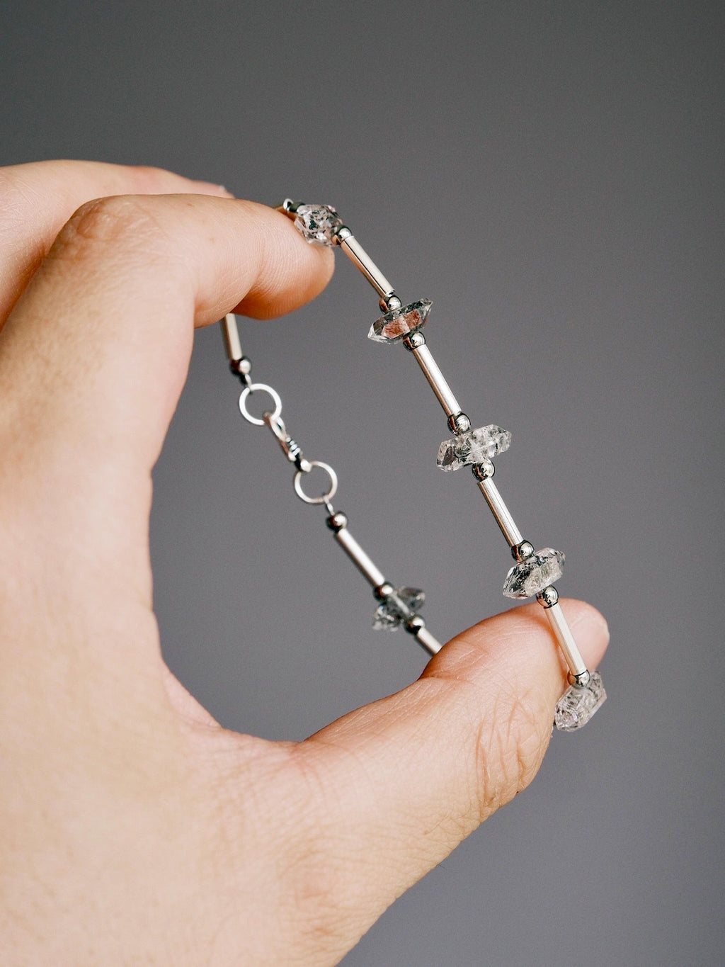 Handheld men’s Herkimer quartz bracelet showing raw crystal texture, silver tube details, and minimalist masculine style