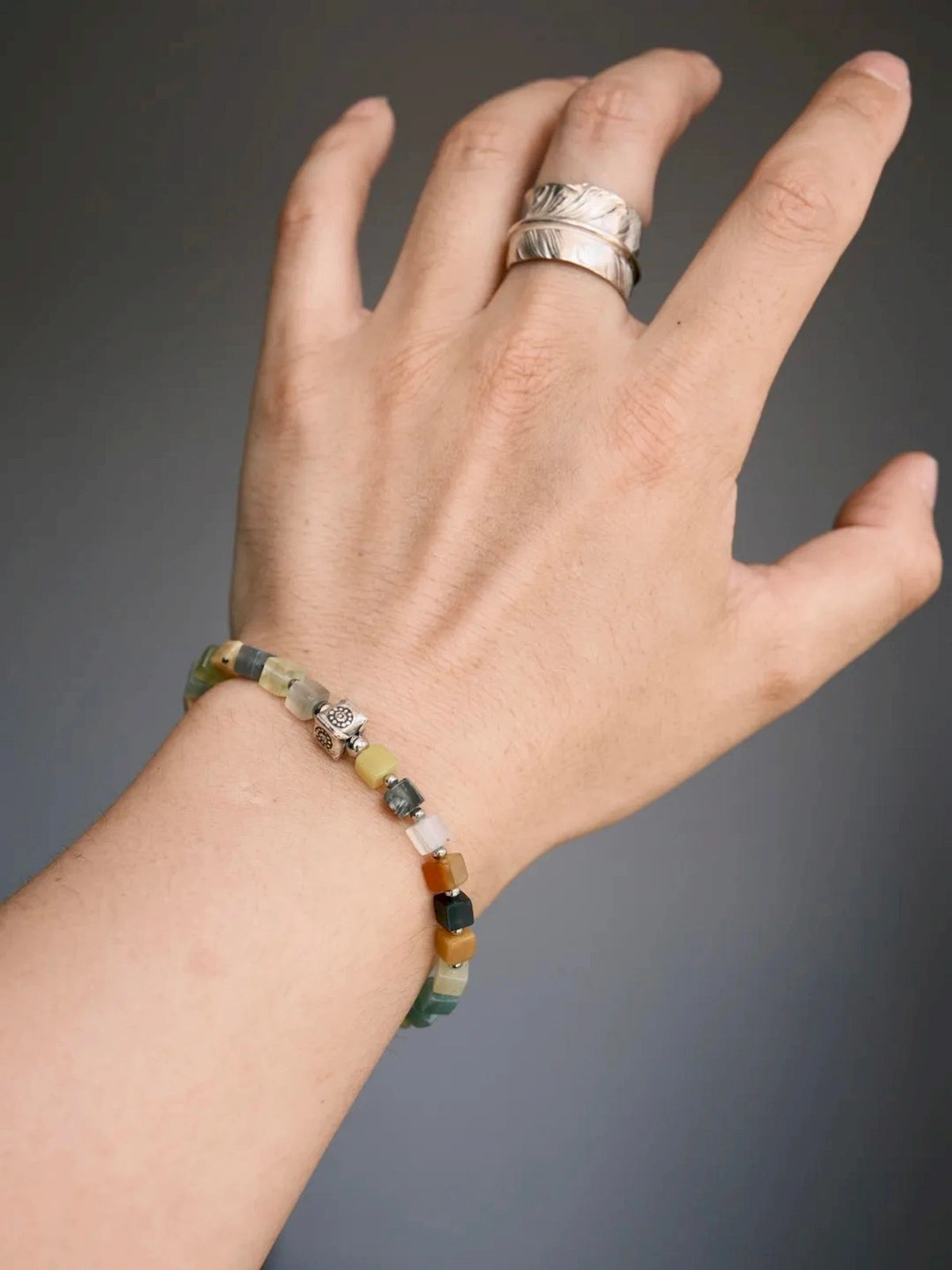 Men’s Xiuyu jade bracelet worn on wrist, silver feather accent, grounded daily wear jewelry