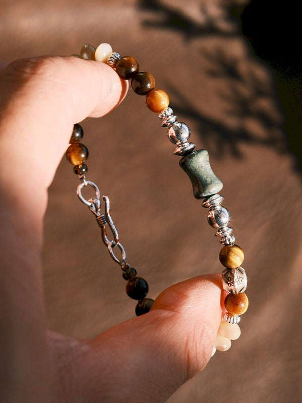 Close-up of tiger eye, green agate and 925 sterling silver details on the Ochre Monarch men’s bracelet in warm sunlight