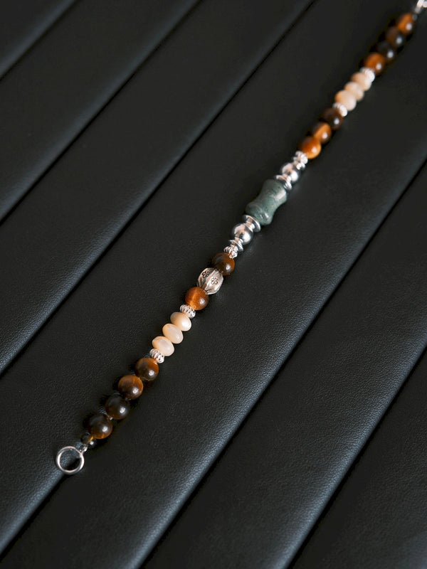Full-length Ochre Monarch bracelet displayed on black leather, showing its tiger eye, mother-of-pearl and silver bead sequence