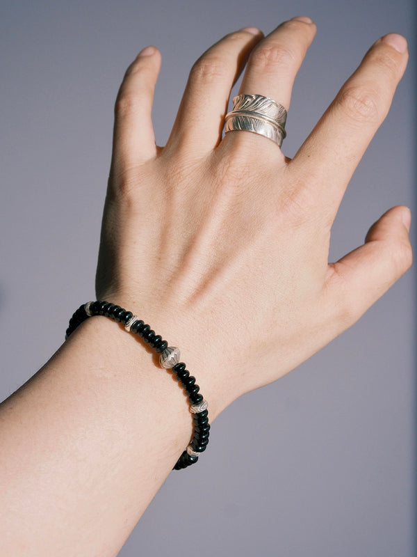 Man wearing the Dawn Sentinel black onyx bracelet with minimalist silver rings