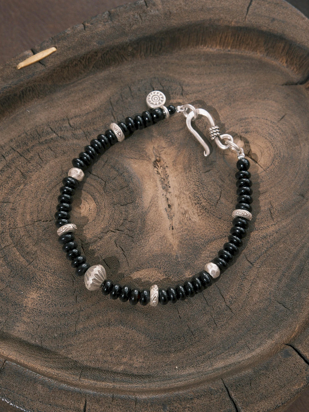 Close-up of flat black onyx beads, hammered 925 sterling silver details, and a 925 silver fishhook