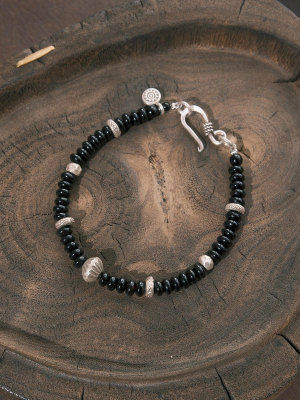 Close-up of flat black onyx beads, hammered 925 sterling silver details, and a 925 silver fishhook