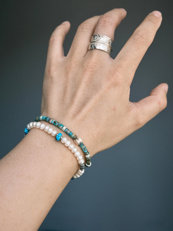 Pearl Rebel stacked with a slim turquoise bracelet, showing white pearls and blue accents