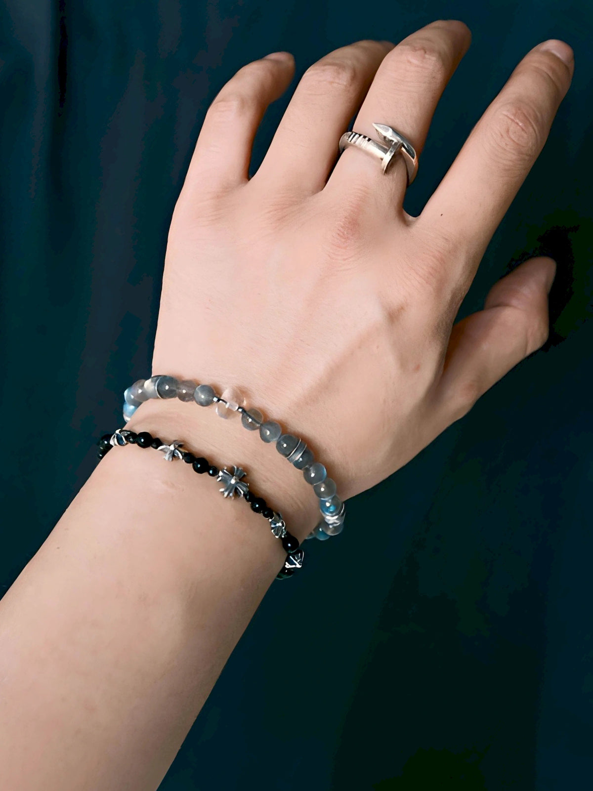 Grey Sovereign labradorite and clear quartz bracelet worn with a separate black-bead bracelet, against a dark blue textured background.