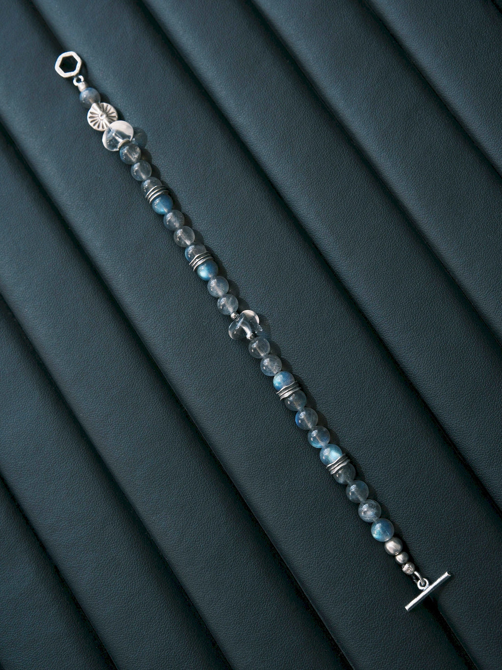 Full Grey Sovereign bracelet extended diagonally over dark blue folds, showing labradorite, clear quartz, silver spacers and open toggle ends.