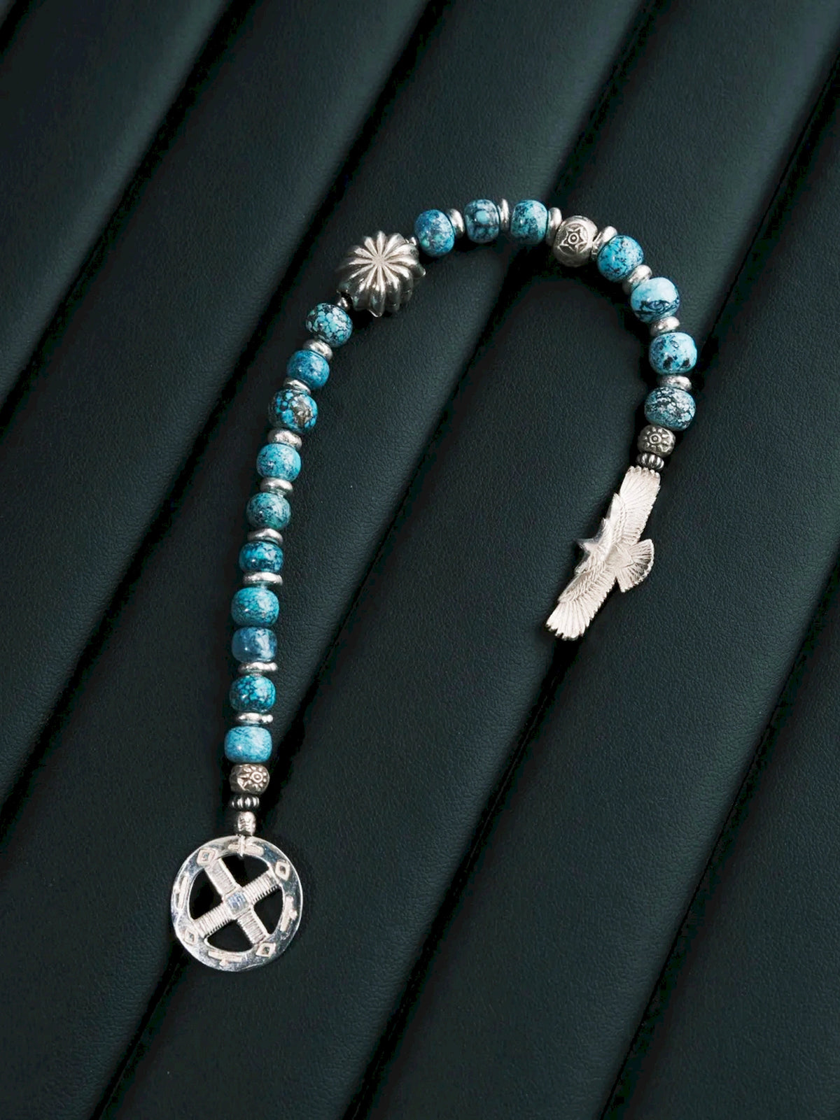 Sun Seeker bracelet laid open in a U shape on a dark textured surface, with the eagle and circular ring separated.