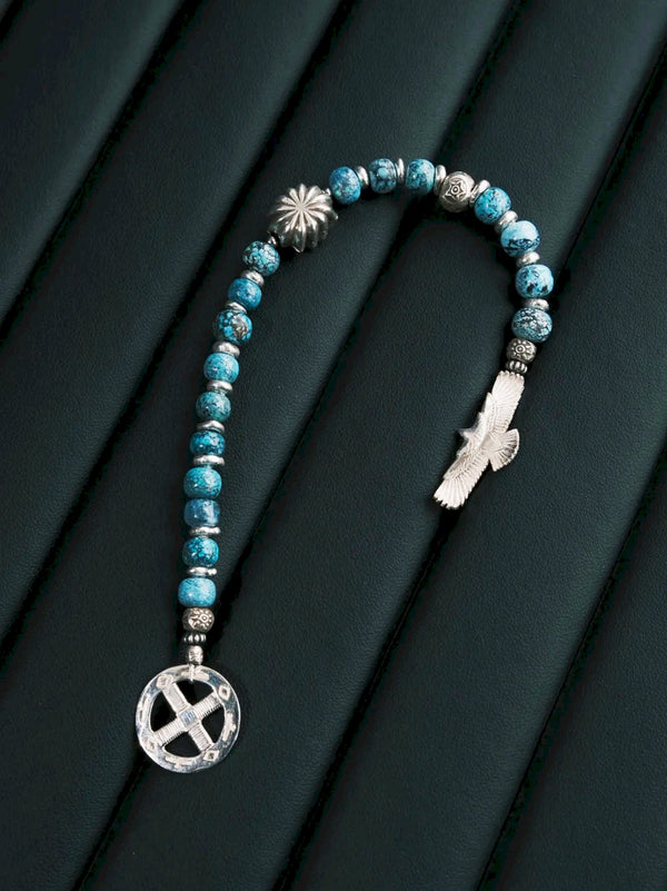 Sun Seeker bracelet laid open in a U shape on a dark textured surface, with the eagle and circular ring separated.