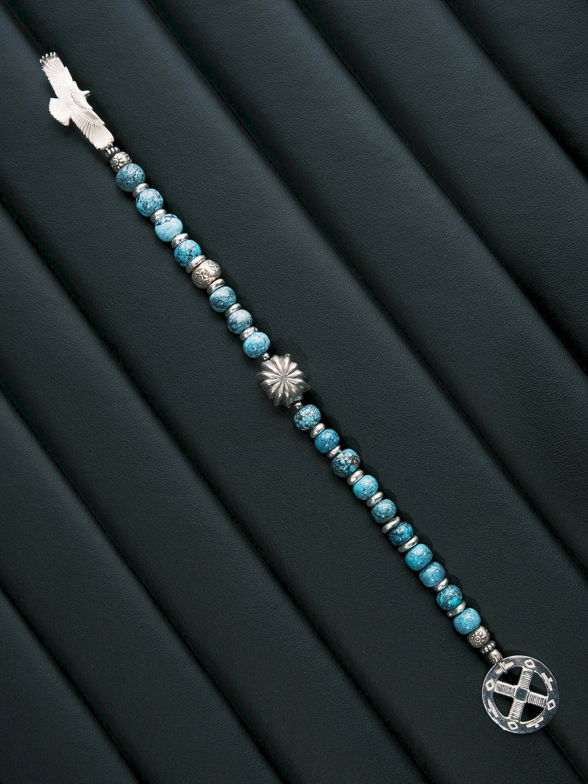 Sun Seeker turquoise bracelet laid diagonally in a straight line, with an eagle at one end and a circular ring at the other.