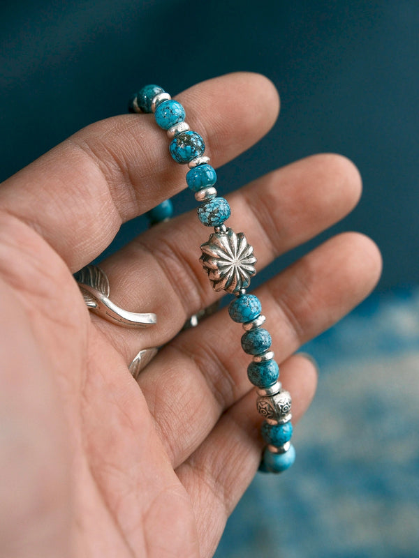 Sun Seeker bracelet worn against dark clothing, with the eagle clasp visible below a cuff and a ring on the hand.