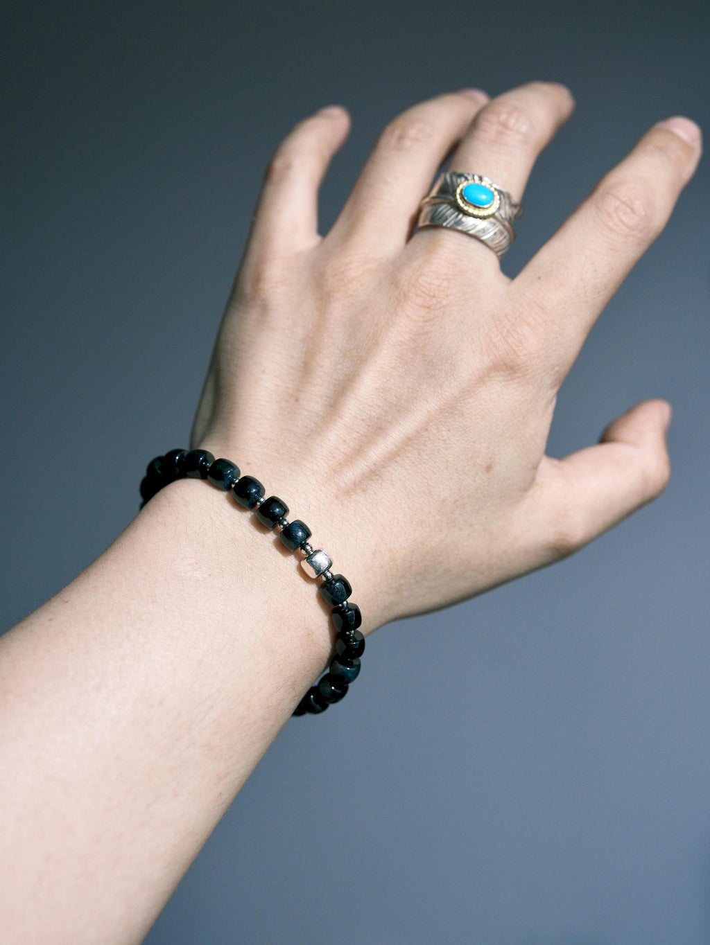 Blue Strategist dark blue bracelet worn alone on a wrist, with a textured silver-tone accent at the front.