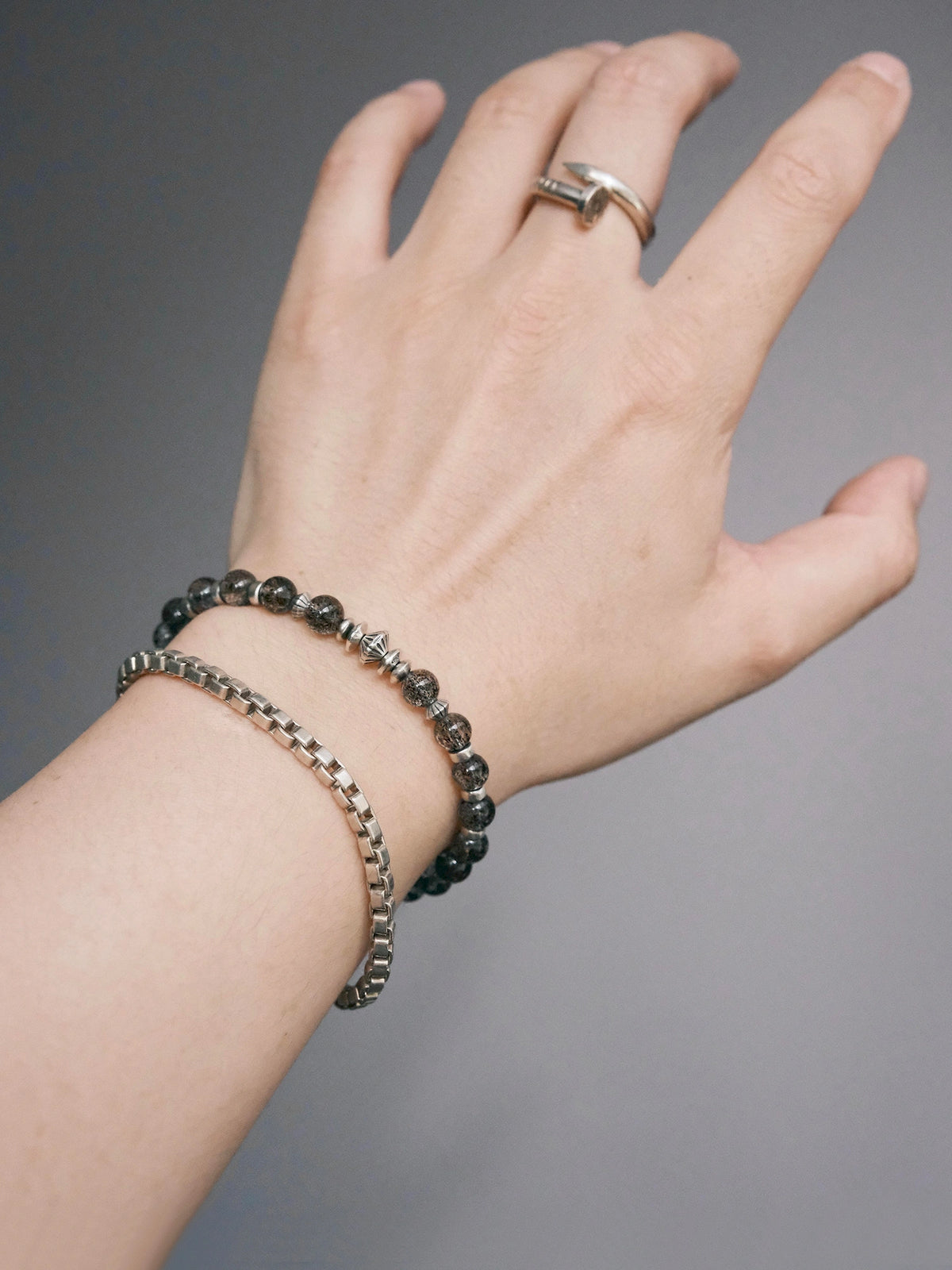 Shadow Sentinel bracelet beside a chain bracelet, with its geometric accents visible across the wrist.