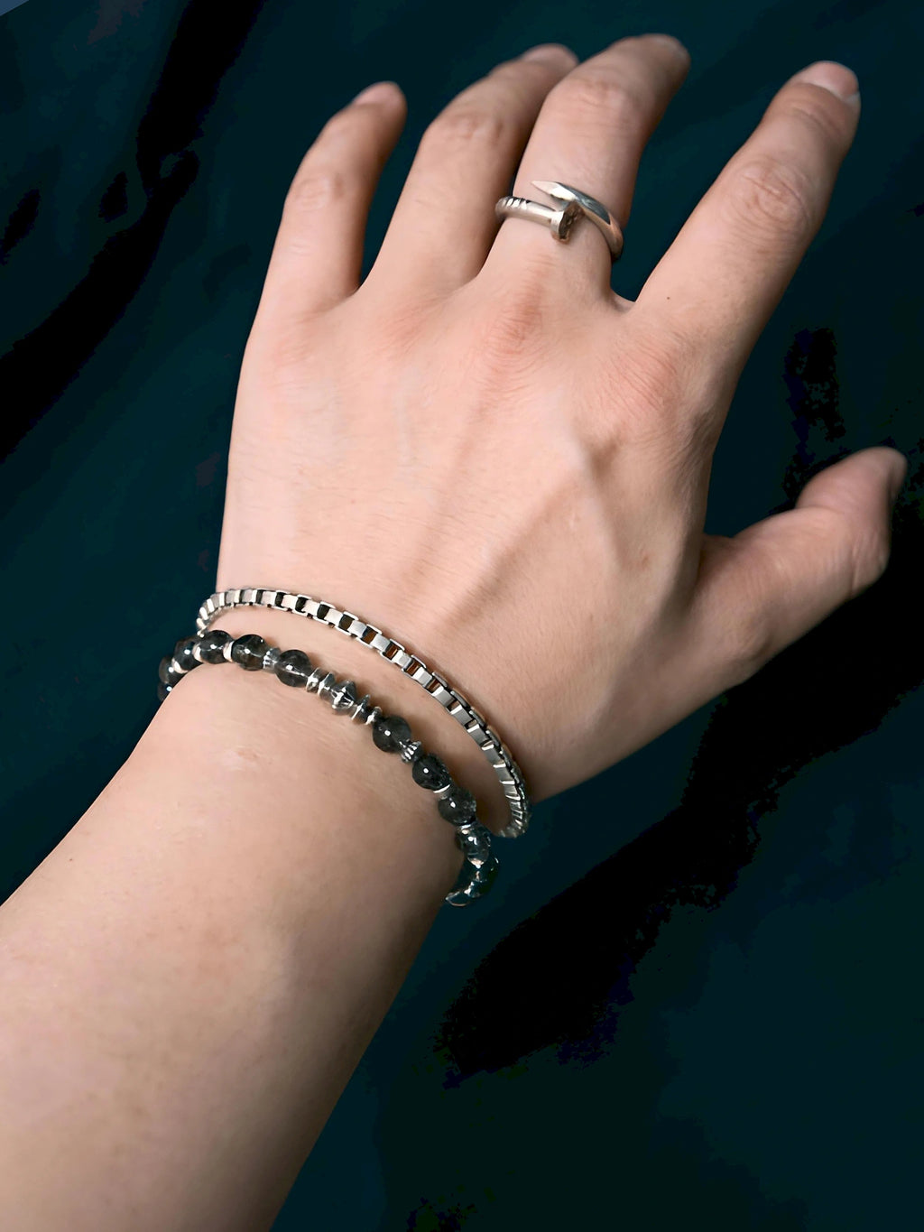 Stackable styling layered style Shadow Sentinel worn with a chain bracelet against dark clothing.