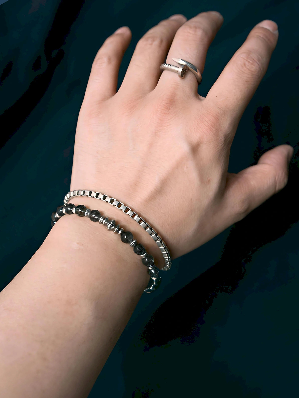 Stackable styling layered style Shadow Sentinel worn with a chain bracelet against dark clothing.