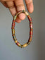 Earth Nomad Picasso jasper bracelet with gold-tone hematite spacers held against a gray background.