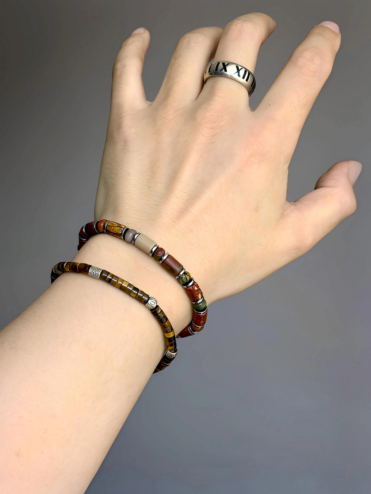 Silver-tone Earth Nomad bracelet worn with a slimmer brown beaded bracelet and a silver-colored ring.