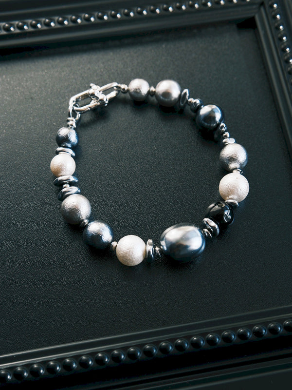 Quiet Rebel men's bracelet in a closed circle on a black tray, showing round and oval beads with silver-tone spacers.