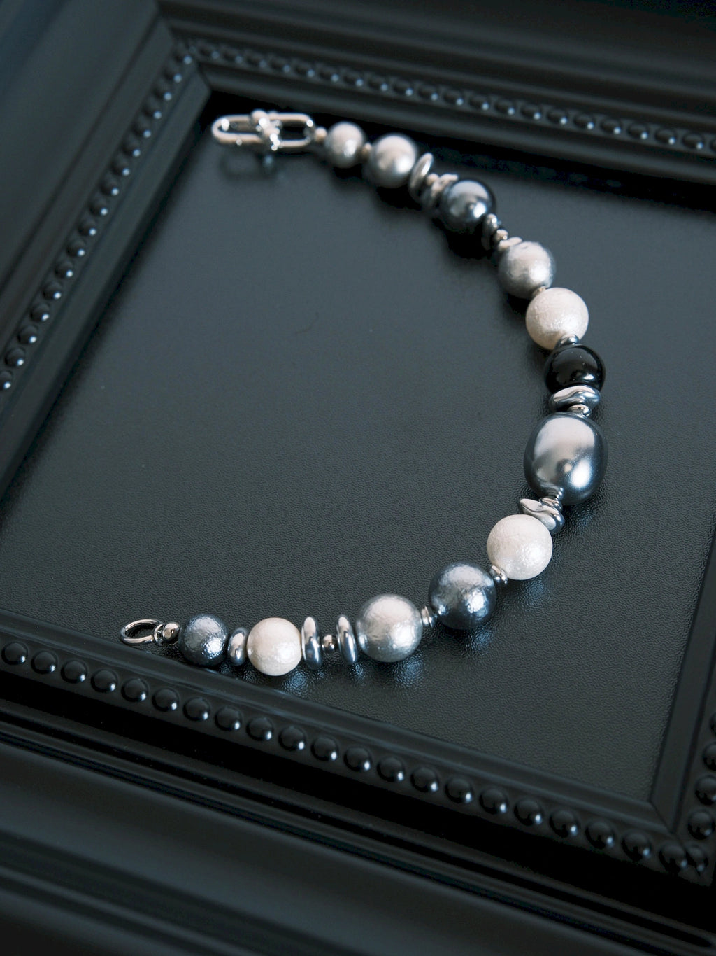 Quiet Rebel bracelet laid open on a black tray, with the horseshoe clasp and opposite end ring separated.