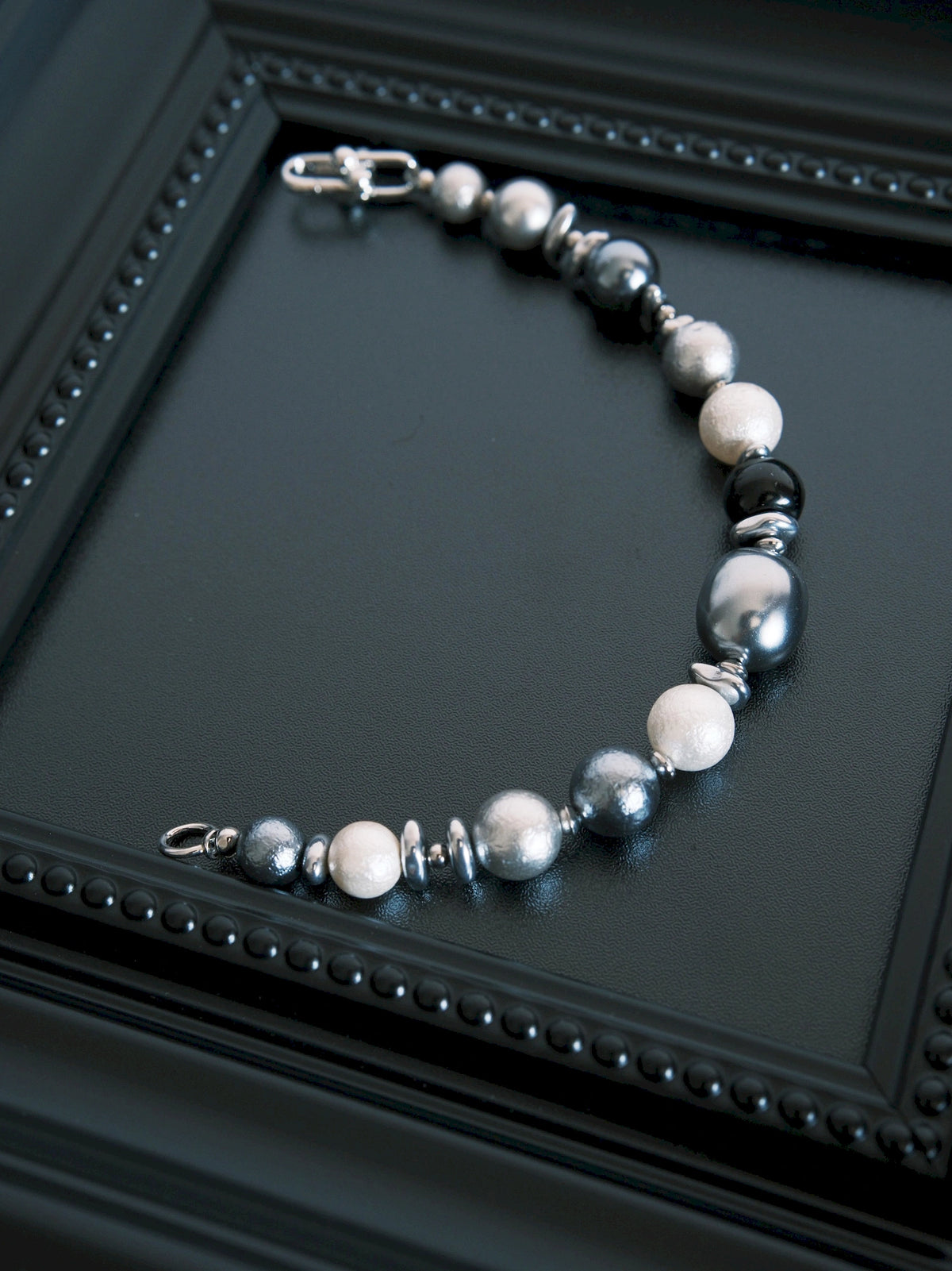 Quiet Rebel bracelet laid open on a black tray, with the horseshoe clasp and opposite end ring separated.