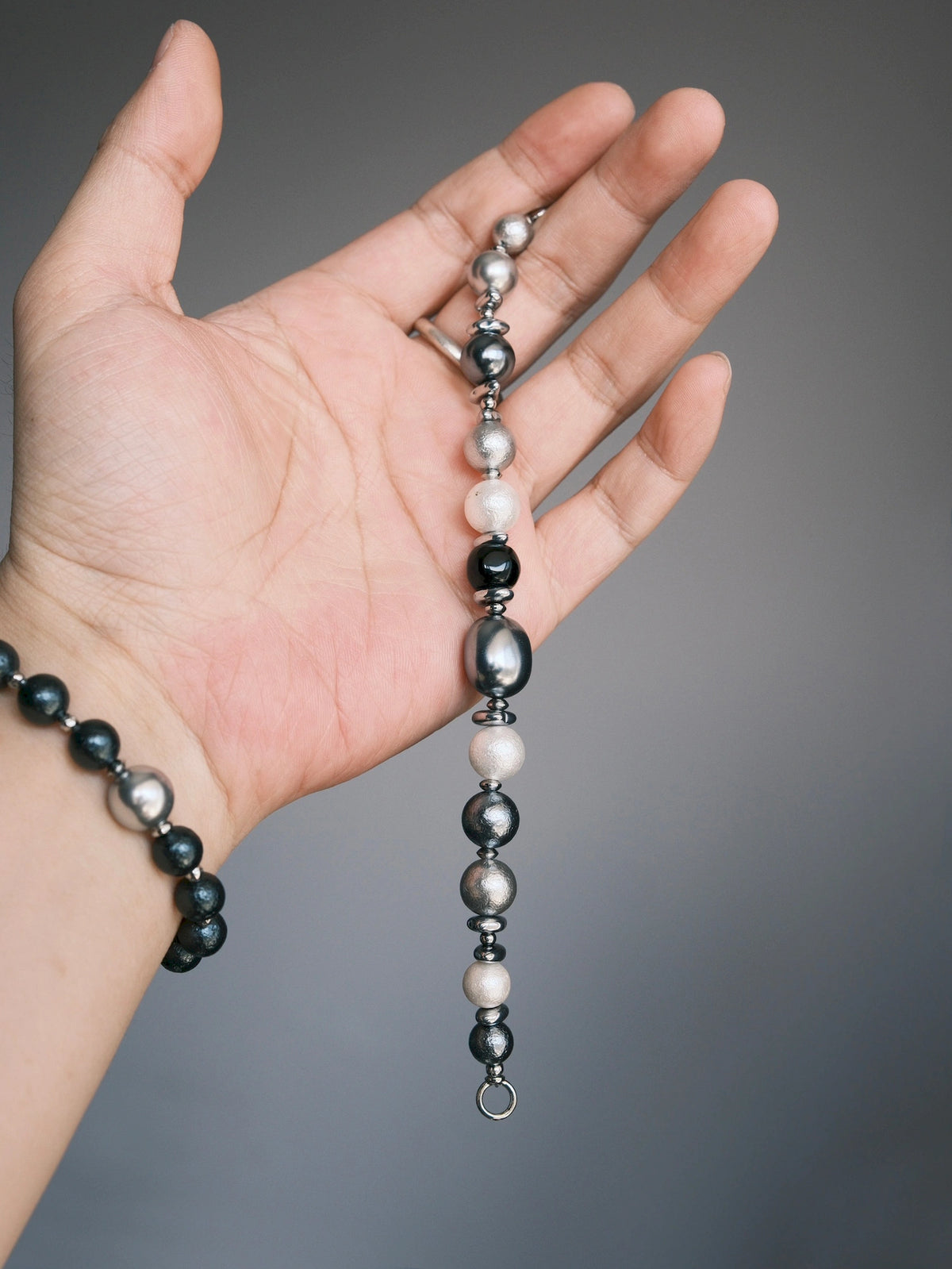 Quiet Rebel bracelet draped down an open palm, with a separate black beaded bracelet worn on the wrist.