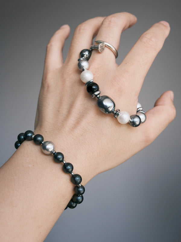 Quiet Rebel bracelet resting across the back of a hand beside a ring and a separate black beaded bracelet.