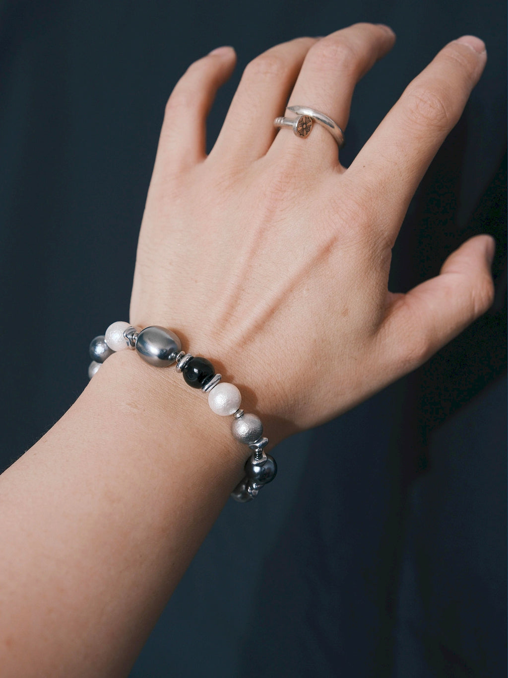 Quiet Rebel bracelet worn on the wrist against a dark background, with round beads and a reflective oval bead visible.