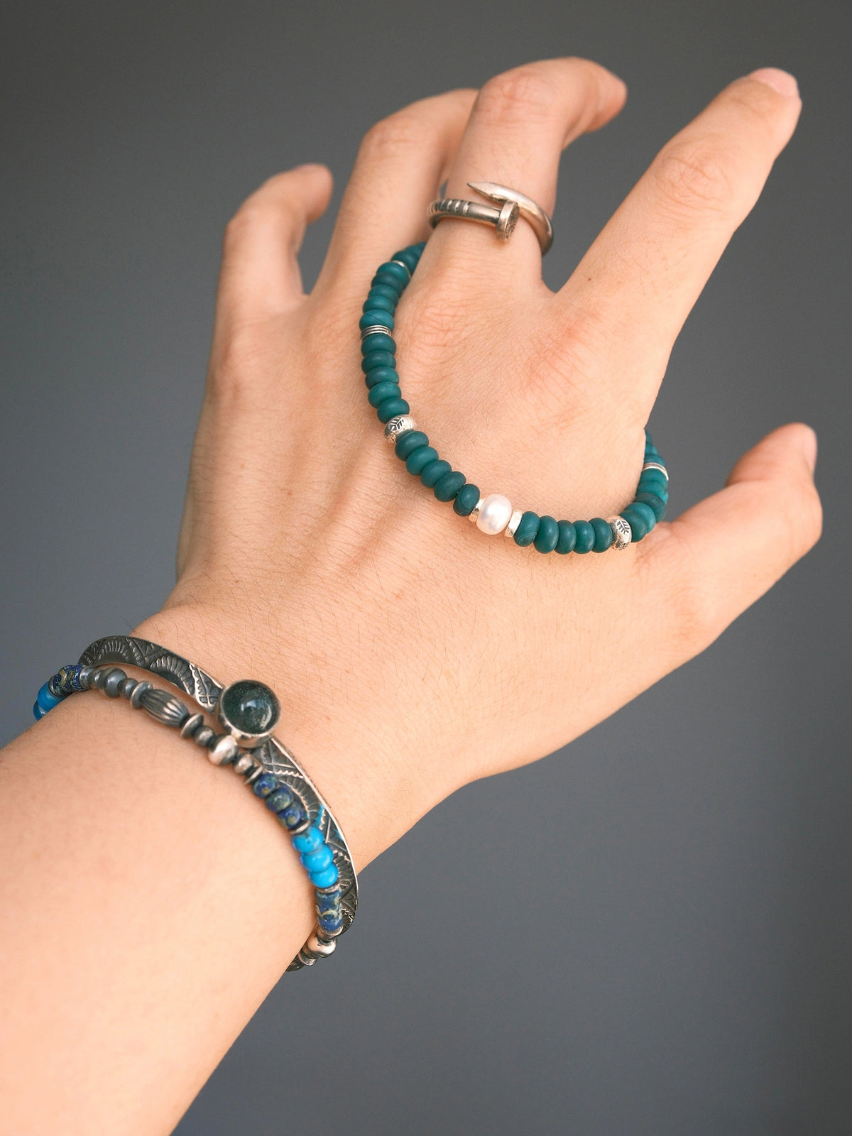 Forest Keeper green agate bracelet draped over the back of a hand above a wrist stack, with a white pearl at the front.
