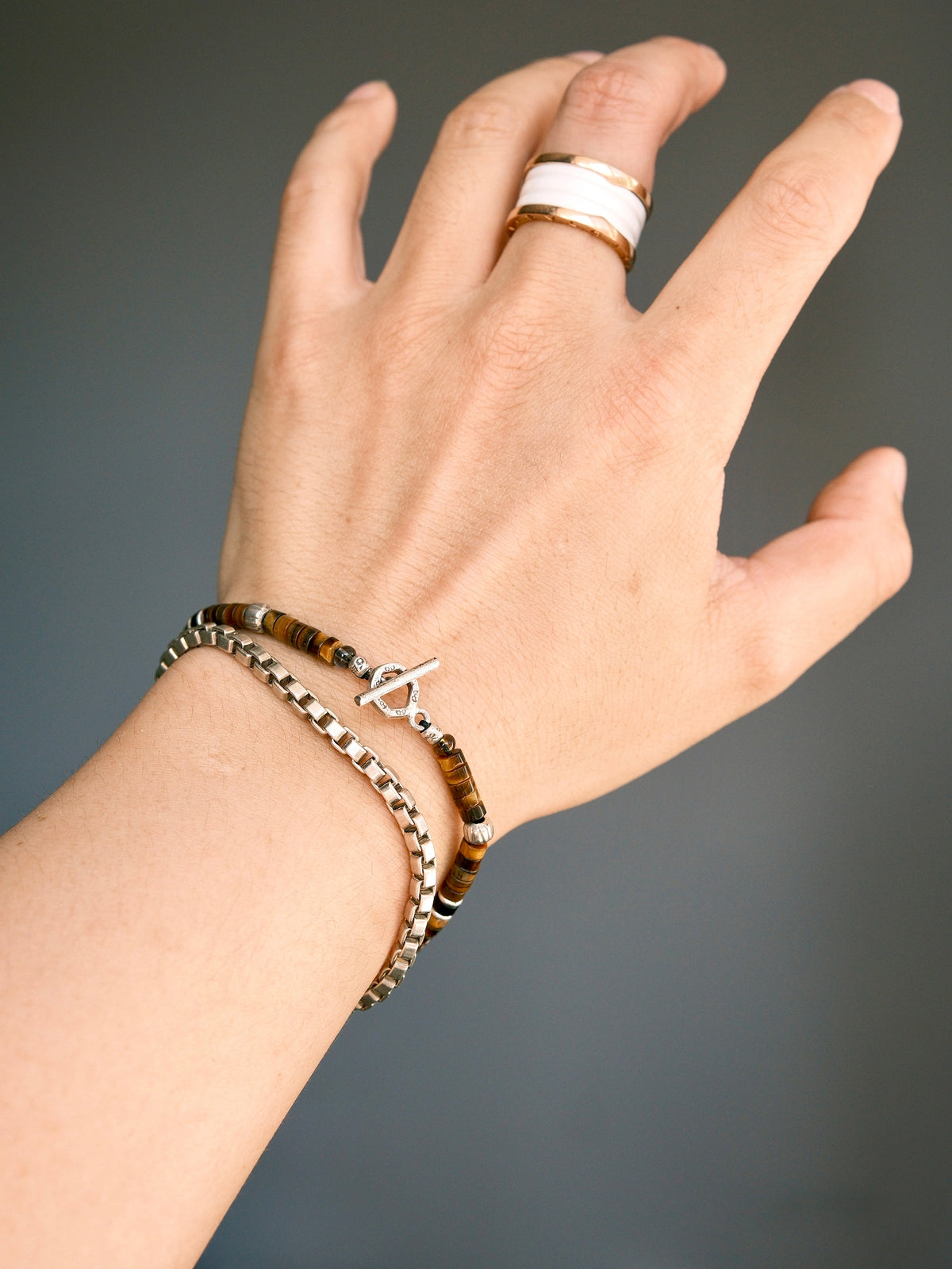 Umber Regent worn with a separate silver-tone chain bracelet, showing the toggle clasp; a ring is also visible.