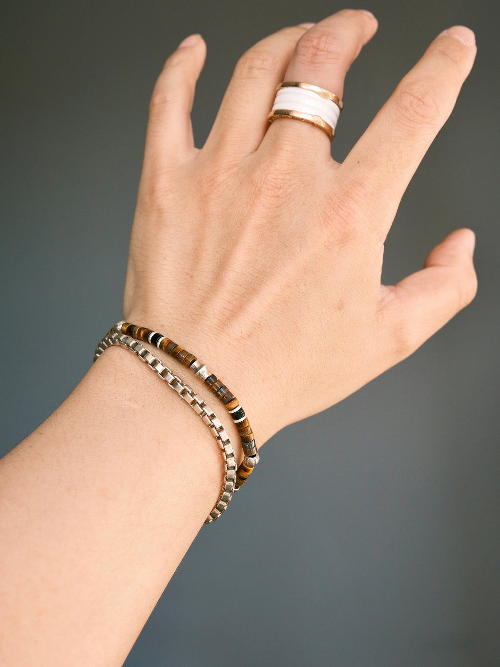 Umber Regent tiger eye bracelet on the wrist beside a separate silver-tone chain, with the silver focal spacer facing up.