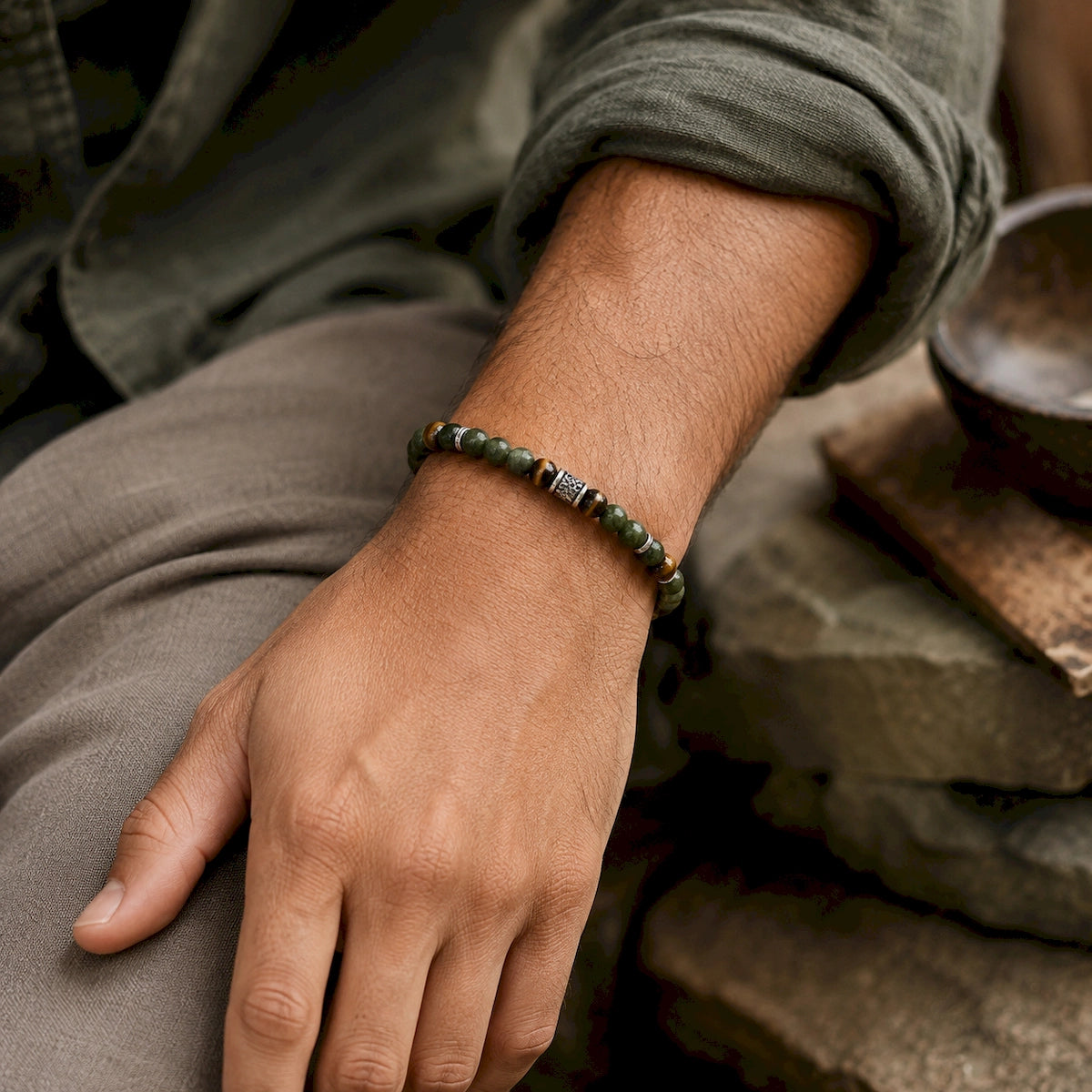 Man wearing an earthy green and brown stone bead bracelet with silver-tone details
